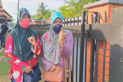 Aminah (kanan) bersama kakaknya, Asmah menunjukkan kesan dakwat pada jari kelingking selepas selesai membuang undi di pusat pengundian di SK Pontian pada Rabu.