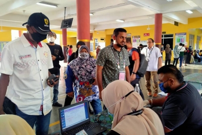 Sreanandha (kanan) membuat semakan sebelum membuang undi di Sekolah Kebangsaan Taman Hi Tech Kulim pada Rabu.