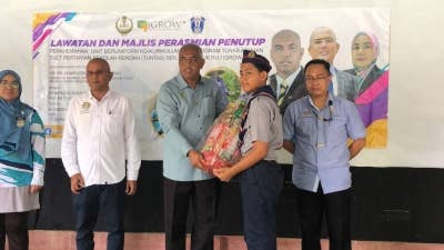 Khairudin (tengah) menyampaikan hadiah kepada peserta yang menyertai perkhemahan unit beruniform kokurikulum dan program Tunas Asuhan TVET Pertanian Sekolah Rendah (Tuntas) di Kompleks Desa Warisan IGROW, Kampung Gajah.
