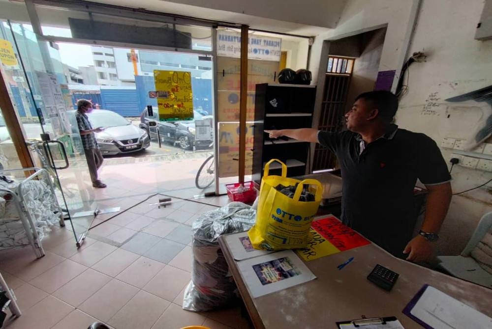 Ram menunjukkan arah air yang memasuki kedainya apabila hujan lebat melanda.