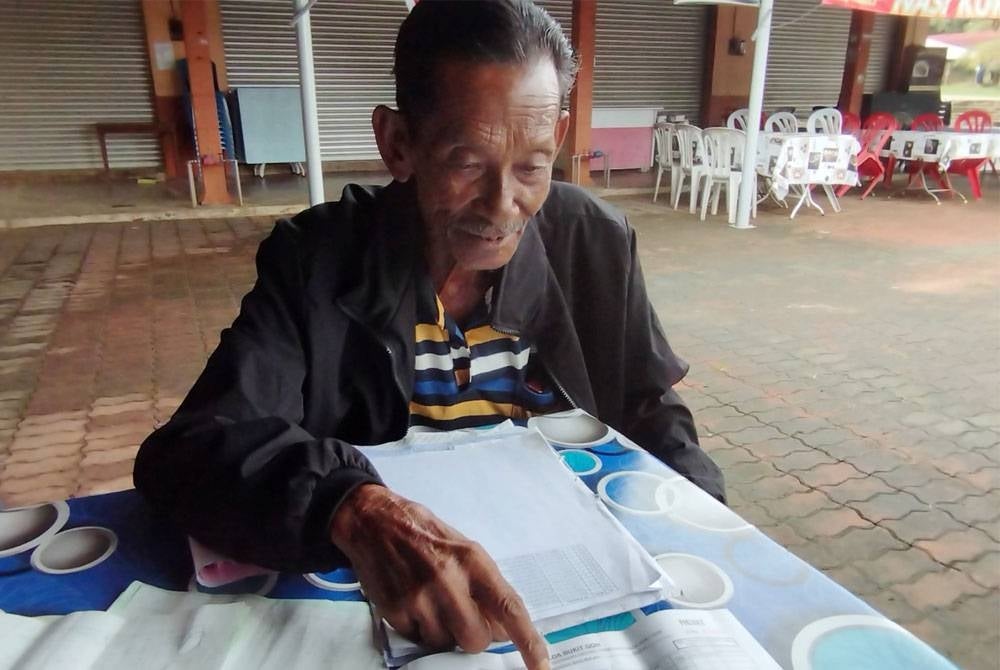 Mohd Nazar menunjukkan resit penerima wang tunai yang diperolehi daripada koperasi Felda selepas membuat penjualan buah sawit.