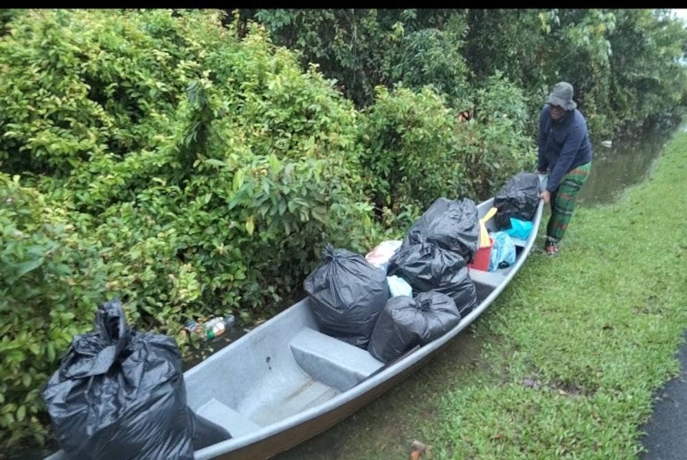 
Mohd Sayuti menolak perahunya yang memuatkan barangan keperluan untuk berpindah ke PPS Gual Periuk.