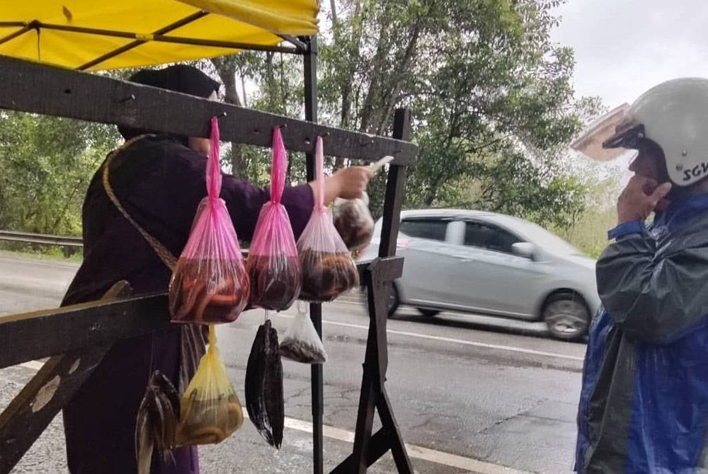 Norie Rafida menjual belut kepada pelanggan di Jalan Pasir Mas - Rantau Panjang pada Ahad.