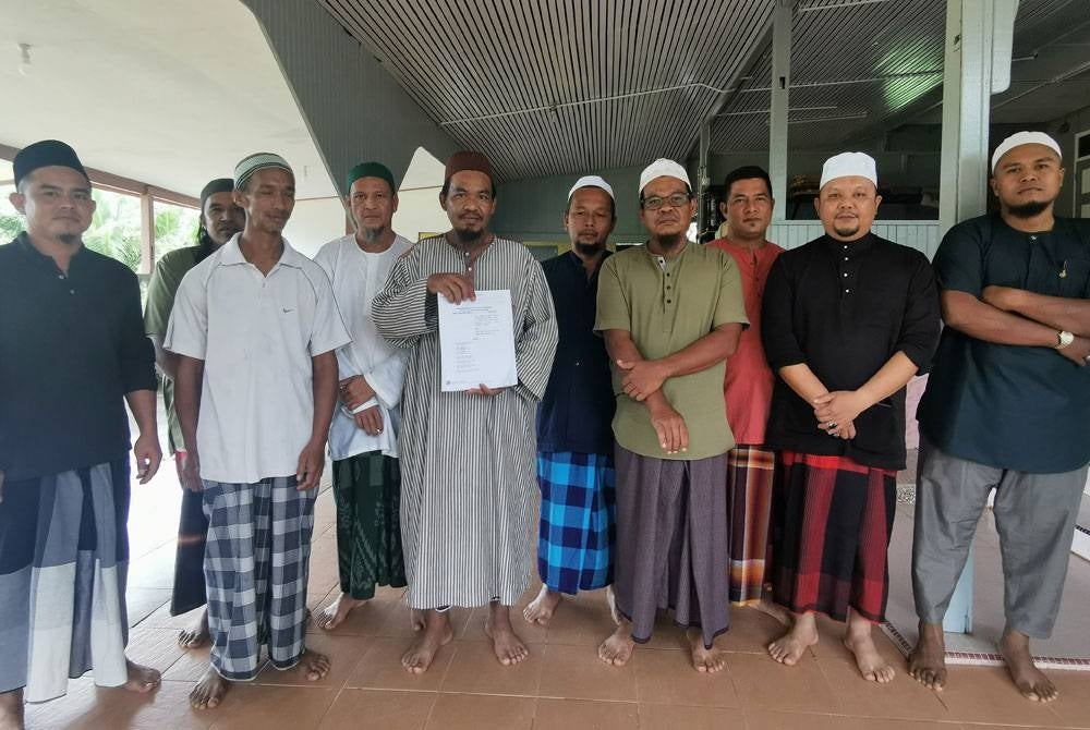 Mohd Sanizan Abd Rahman, 44, menunjukkan antara surat mahkamah berhubung proses pengambilalihan tanah di Kampung Pulau Sekati di Kuala Terengganu.