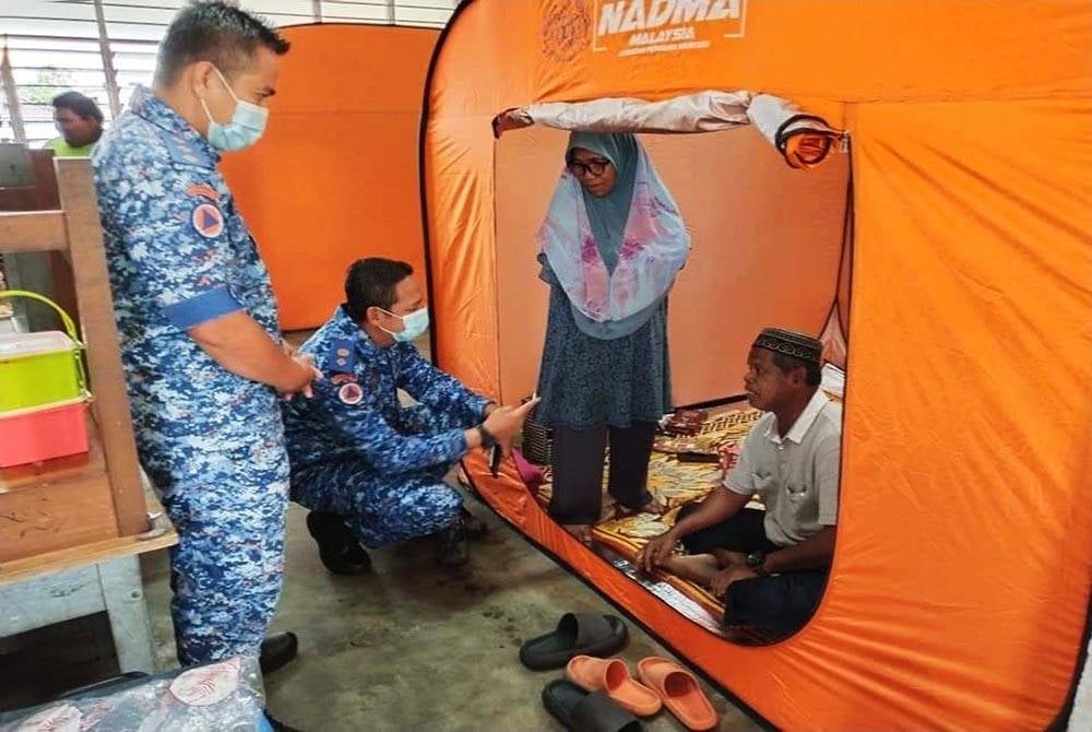 Pengarah Angkatan Pertahanan Awam Malaysia (APM) Terengganu, Mohd Rosman Abdullah (dua dari kiri) meninjau keadaan mangsa banjir terjejas yang dipindahkan di pusat pemindahan sementara (PPS) di Sekolah Kebangsaan (SK) Tok Jembal di daerah Kuala Nerus, Terengganu.