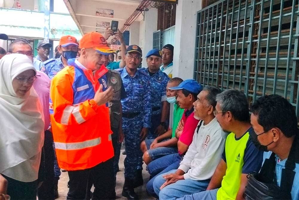 Armizan (tengah) menyantuni mangsa banjir yang berada di PPS SMK Seri Semantan pada Selasa.