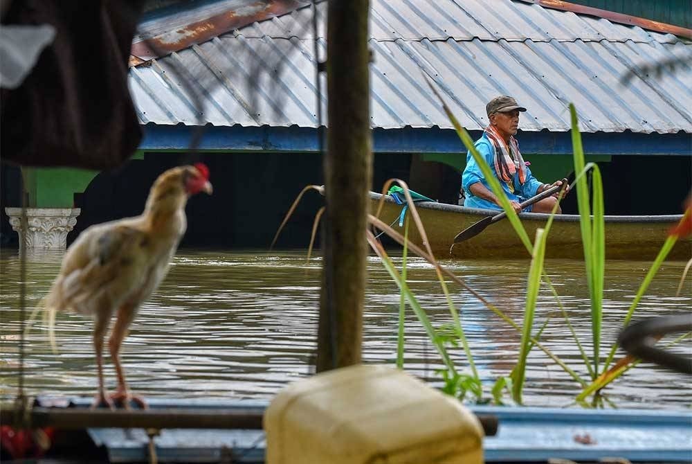 Penduduk menggunakan sampan untuk meninjau keadaan rumah mereka yang ditenggelami banjir ketika tinjauan di Kampung Tersang, Rantau Panjang pada Selasa. - Foto Bernama