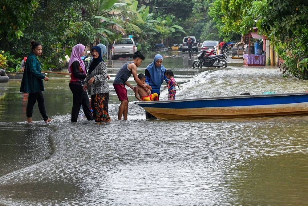 Penduduk menggunakan perkhidmatan sampan untuk melakukan kegiatan harian berikutan kawasan kampung masih ditenggelami banjir ketika tinjauan di Kampung Tersang, Rantau Panjang, Kelantan pada Selasa.- Foto Bernama