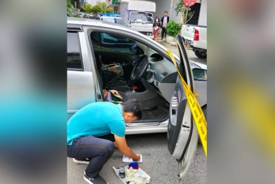 Anggota polis sedang menyiasat sebuah kereta yang ditinggalkan suspek di lokasi kejadian.