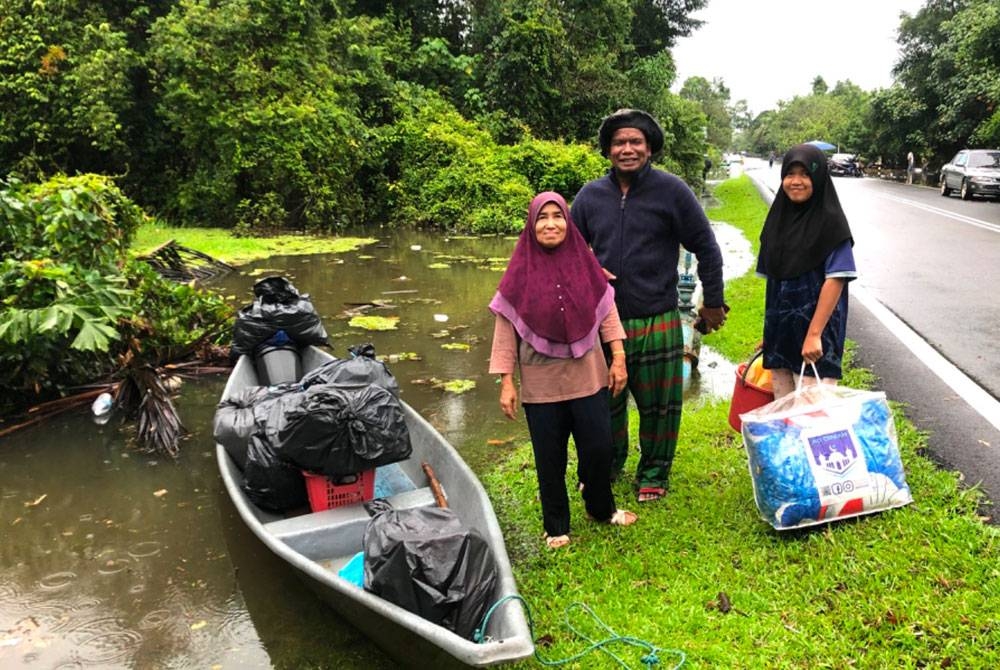 Fatimah (kiri) bersama Mohd Sayuti membawa sebahagian baju di dalam plastik ke PPS.