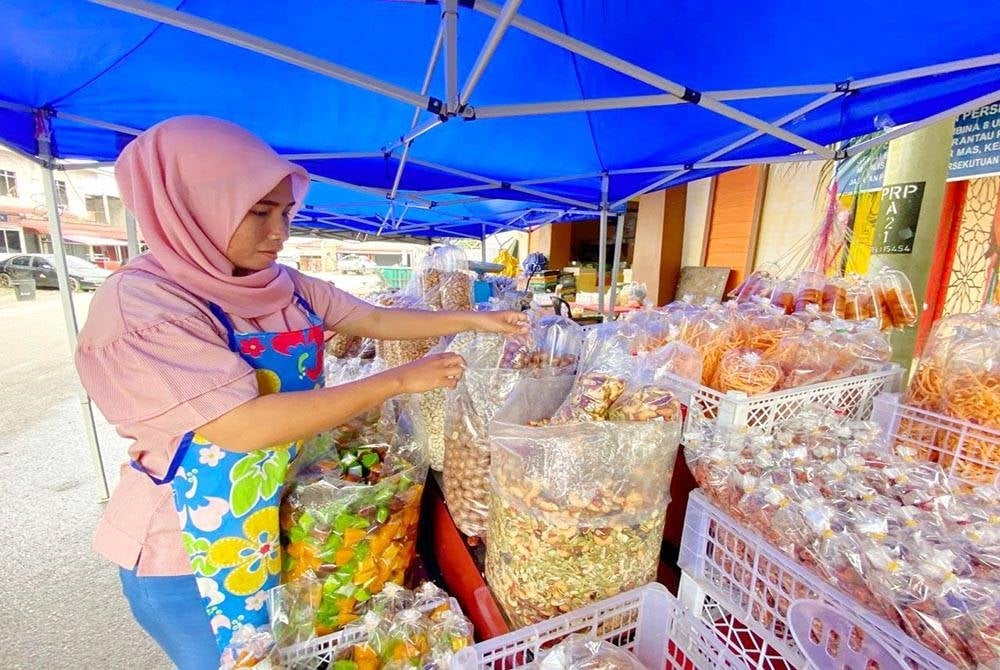 Subaini menyusun bahan jualan yang baharu dibawa masuk untuk jualan cuti sekolah namun hampa apabila pengunjung tiada.