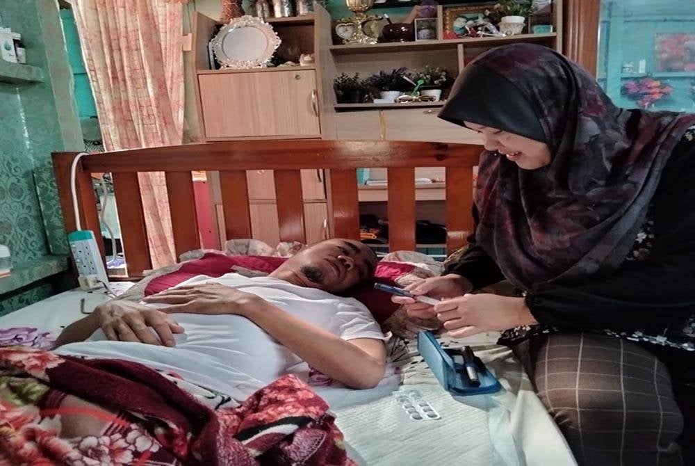 Noraini membantu mencucuk insulin di lengan Rozaimi ketika ditemui di rumahnya di Kampung Bunut Payong pada Rabu.