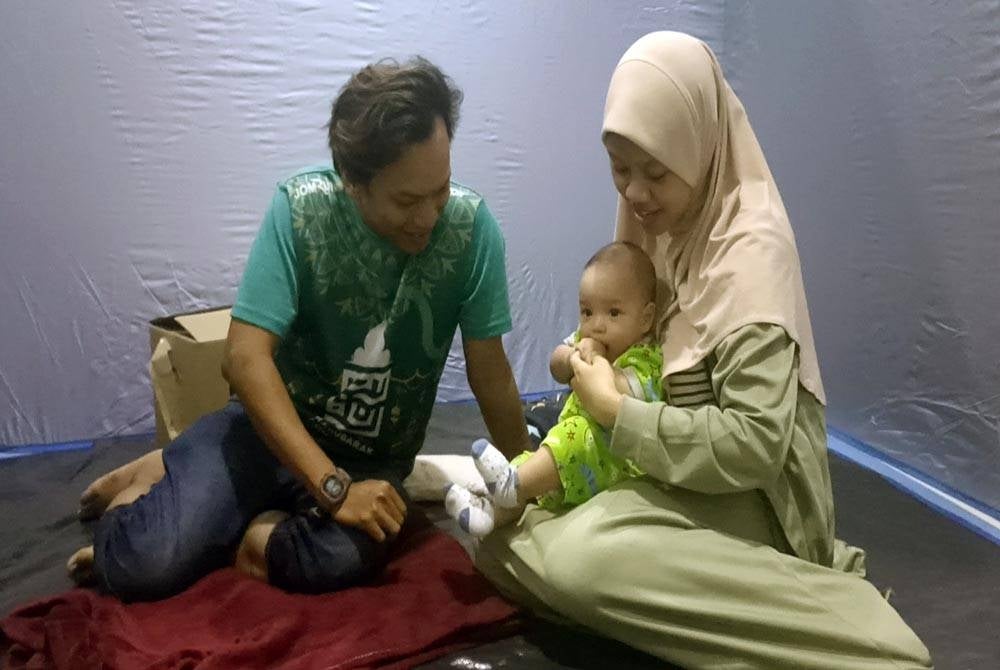 Farah Ain bersama suami, Mohd Azramzaki dan bayi berusia empat bulan kini berlindung di PPS Dewan Muafakat Bandar Penawar selepas rumah mereka dilanda banjir.