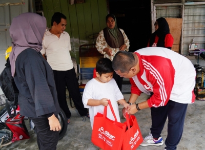 Nik Justin (kanan) memberi sumbangan Kit Bantuan Bencana Sinar Karangkraf kepada seorang kanak-kanak pada program berkenaan.