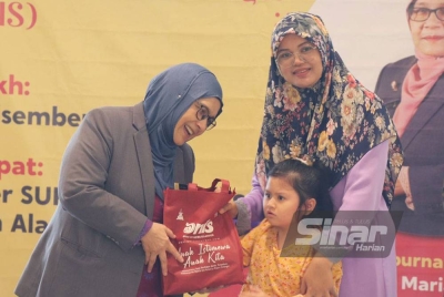 Dr Siti Mariah (kiri) menyampaikan sumbangan pada Majlis Penyerahan Bantuan Khas ANIS 2022 di Bangunan Sultan Salahuddin Abdul Aziz Shah di sini pada Rabu.