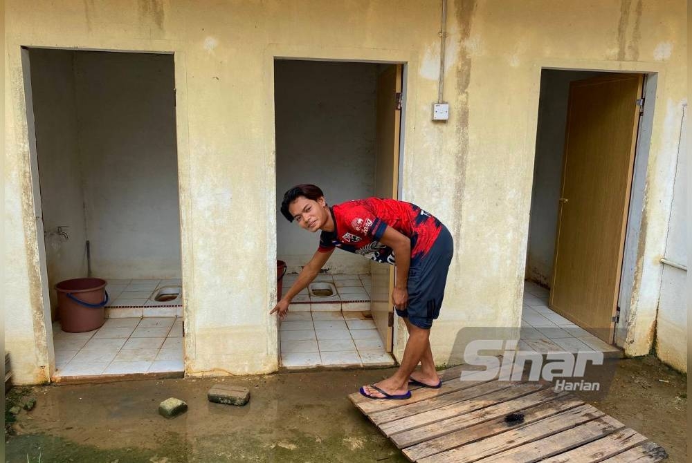 Salah seorang penghuni PPS menunjukkan kedalaman air yang menenggelamkan tandas sejak Sabtu lalu.