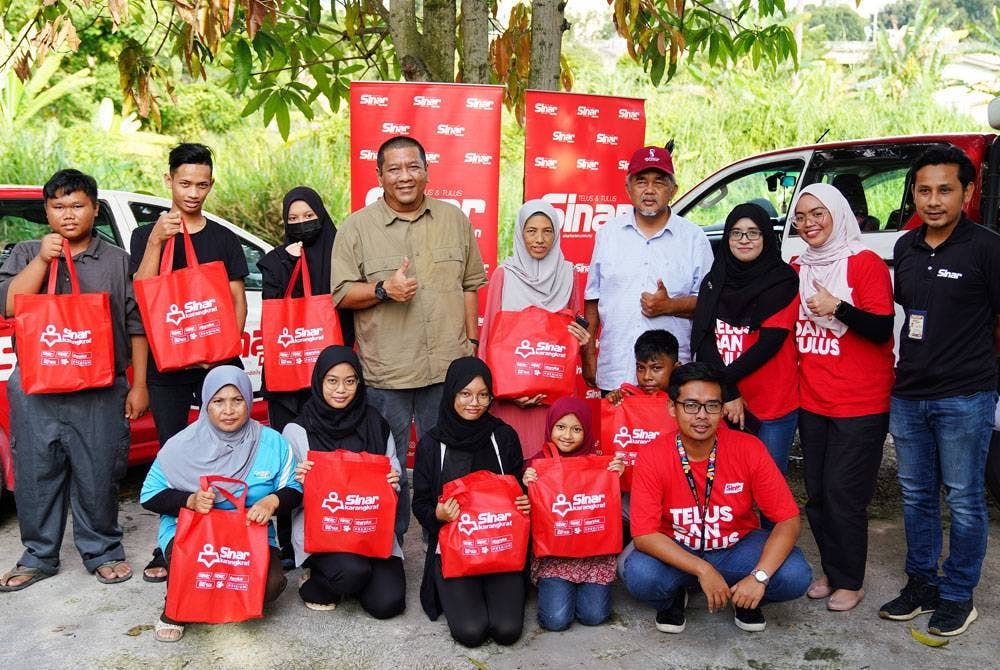 Nik Justin (berdiri, empat dari kiri) dan Hashim (berdiri, empat dari kanan) bergambar bersama penerima sumbangan
kit bantuan bencana di Kampung Kebun Bunga Batu 3, Shah Alam pada Selasa.