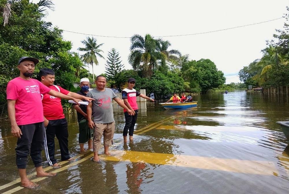 Norhisham (kiri) bersama sebahagian daripada mangsa banjir menunjukkan keadaan banjir termenung yang membelenggu kehidupan mereka di Rantau Panjang.