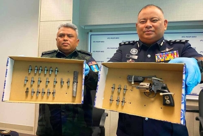 Mohd Nasaruddin (kanan) bersama Mannadzar menunjukkan pistol yang dirampas dalam serbuan tersebut.