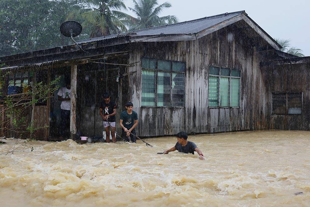 Penduduk meredah arus yang deras selepas rumah mereka dilanda banjir ekoran hujan lebat semasa tinjauan di Kampung Buluh, Kuala Berang, Terengganu pada Ahad. - Foto Bernama