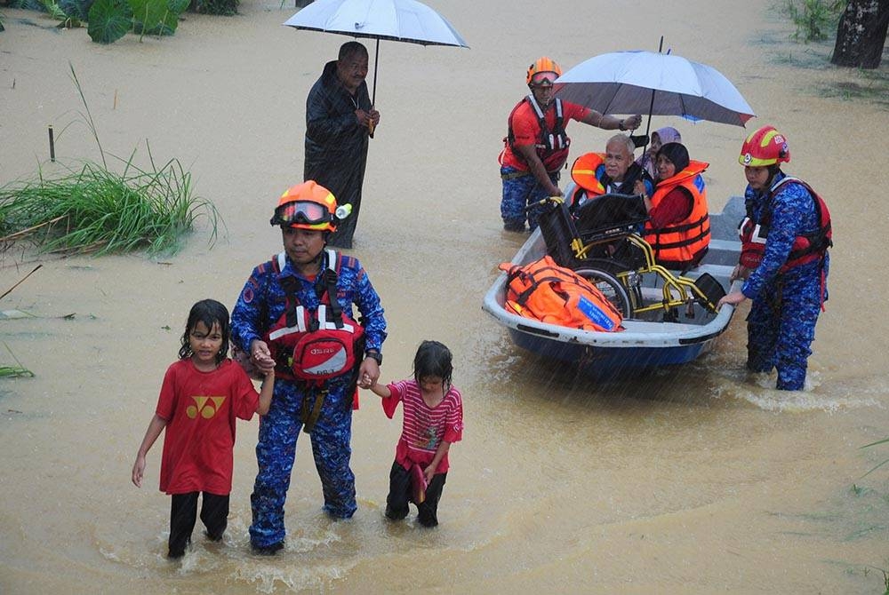 Anggota Angkatan Pertahanan Awam Malaysia (APM) Besut membantu memindahkan mangsa banjir di Kampung Baroh Masin, Hulu Besut pada Ahad. - Foto Bernama