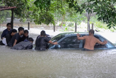 Shukri (kanan) dibantu penduduk setempat menolak keluar keretanya untuk dipindahkan ke tempat yang tinggi berikutan kampung terbabit dinaiki air banjir awal pagi Ahad. - Foto Bernama