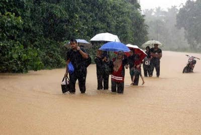 Beberapa penduduk mengharungi banjir untuk ke tempat selamat selepas kampung mereka dilanda banjir semasa tinjauan di Kampung Besut pada Ahad. - Foto: Bernama