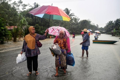 Beberapa penduduk mengharungi air dengan membawa pakaian untuk ke tempat selamat selepas kampung mereka dilanda banjir berikutan hujan lebat berterusan ketika tinjauan di Kampung Tengkawan hari ini. - Foto Bernama