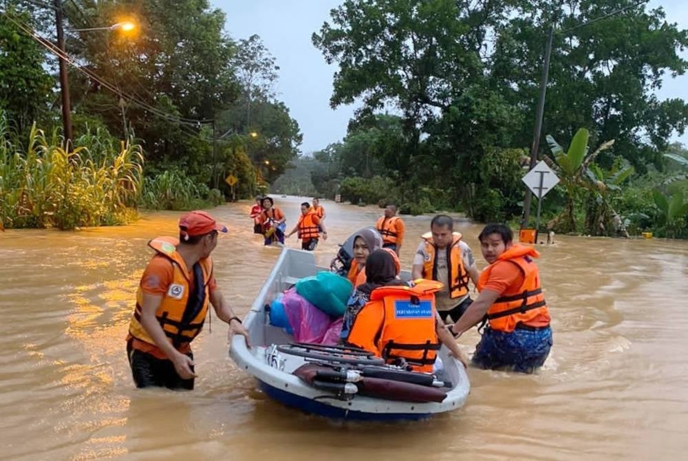 Anggota penyelamat memindahkan mangsa banjir di Kampung Kuala Ping, di Hulu Terengganu. - Foto APM Terengganu