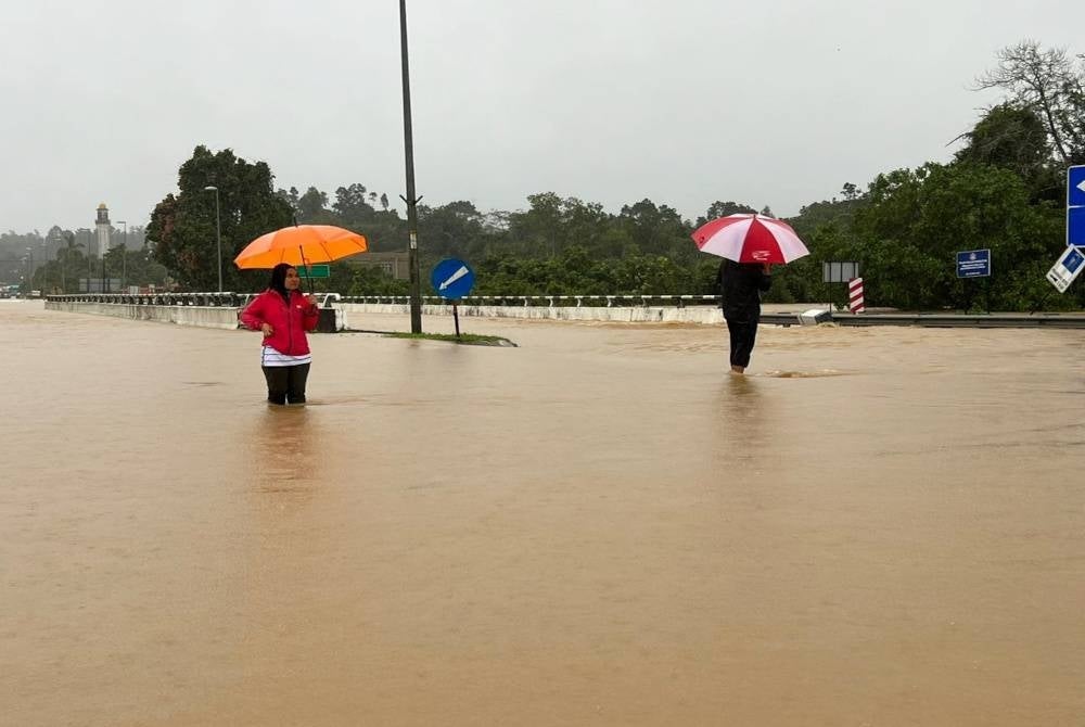 Nur Fazlizai (kiri) berada di jalan yang dinaiki air di daerah Setiu.