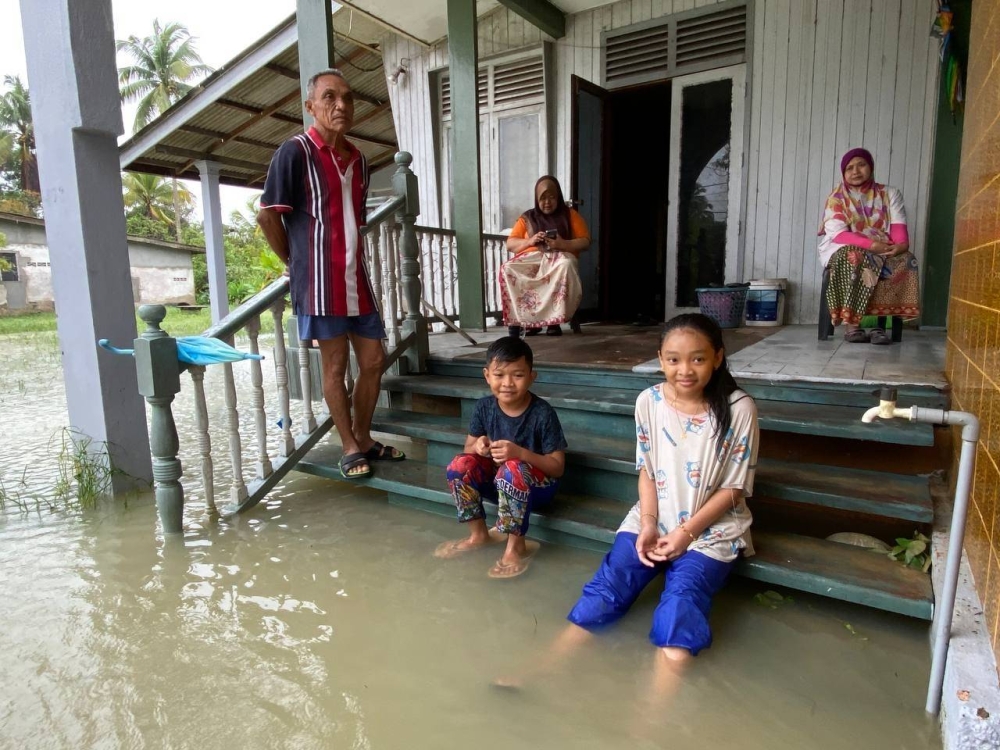 Zaitun (kanan) dan Azilawani (kiri) bersama jiran tetangga mereka melihat situasi banjir sebelum berpindah ke PPS berhampiran.