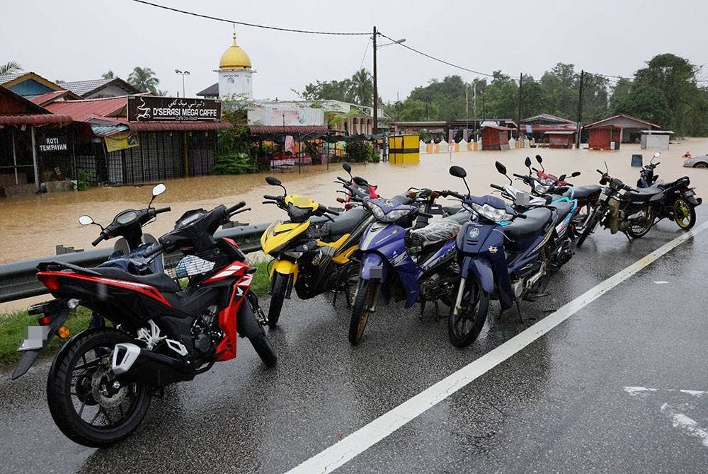 Penduduk meletakkan motosikal mereka di tempat tinggi selepas kediaman mereka dilanda banjir di Kampung Buluh hari ini. - Foto Bernama