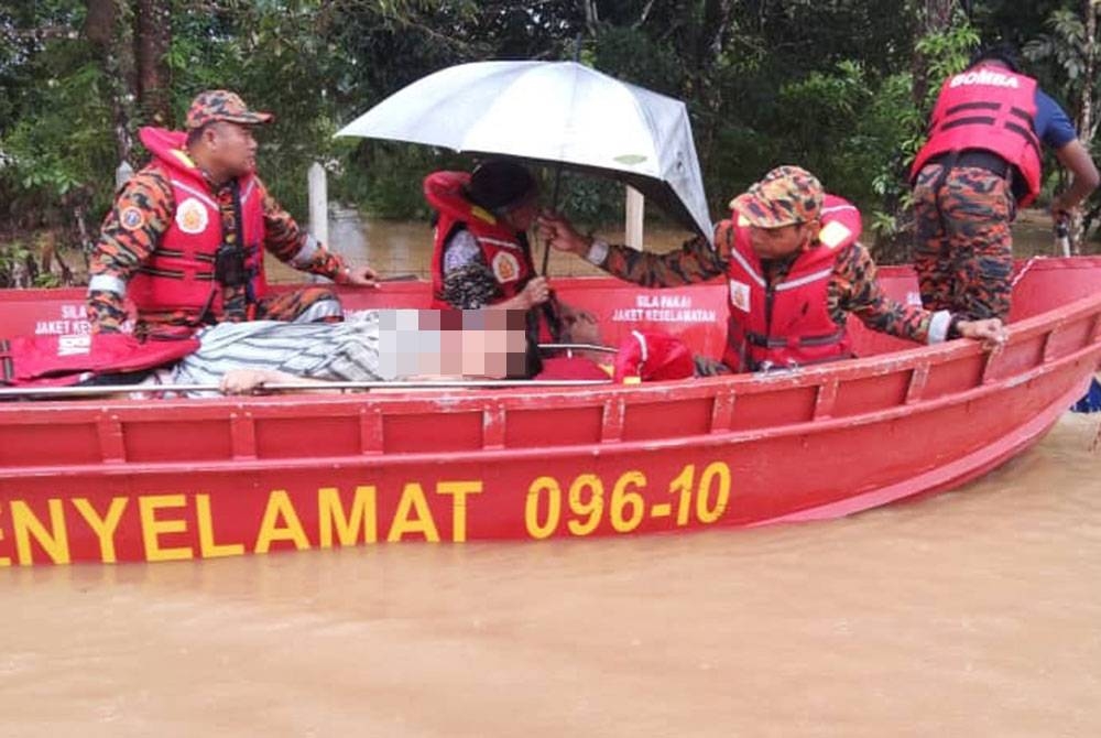 Anggota bomba memindahkan mangsa banjir yang mengalami lumpuh ke PPS setelah rumahnya di Kampung Dadong, Air Putih di Kemaman dinaiki air.