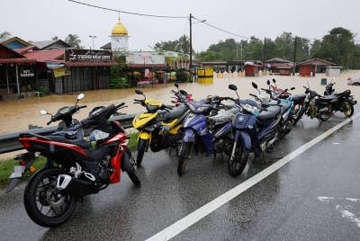Penduduk meletakkan motosikal mereka di tempat tinggi selepas kediaman mereka dilanda banjir di Kampung Buluh hari ini. - Foto Bernama