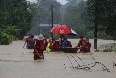Sukarelawan memindahkan mangsa banjir ekoran banjir yang melanda daerah Setiu semasa tinjauan di Kampung Buluh Hilir. - Foto Bernama.