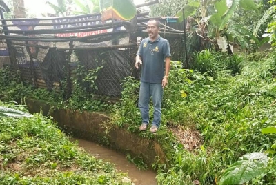 Rosli menunjukkan keadaan longkang di bahagian belakang rumahnya yang didakwa menjadi punca banjir kilat di kawasan itu.