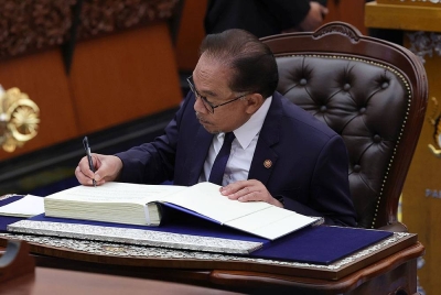 Anwar menandatangani watikah pelantikan selepas mengangkat sumpah sebagai Ahli Parlimen pada Mesyuarat Pertama Penggal Pertama Parlimen ke-15 di Bangunan Parlimen hari ini. - Foto Bernama