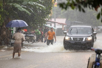 Beberapa kenderaan meredah jalan yang dinaiki air berikutan hujan lebat di Kampung Kubang Kual, Rantau Panjang pada Ahad. - Foto Bernama