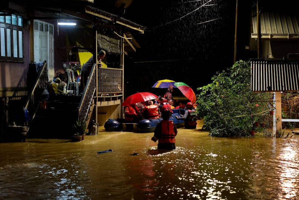 Anggota pasukan JBPM membantu menyelamatkan para penduduk yang terperangkap akibat banjir di Kampung Pulau Rusa Hulu malam tadi. - Foto Bernama