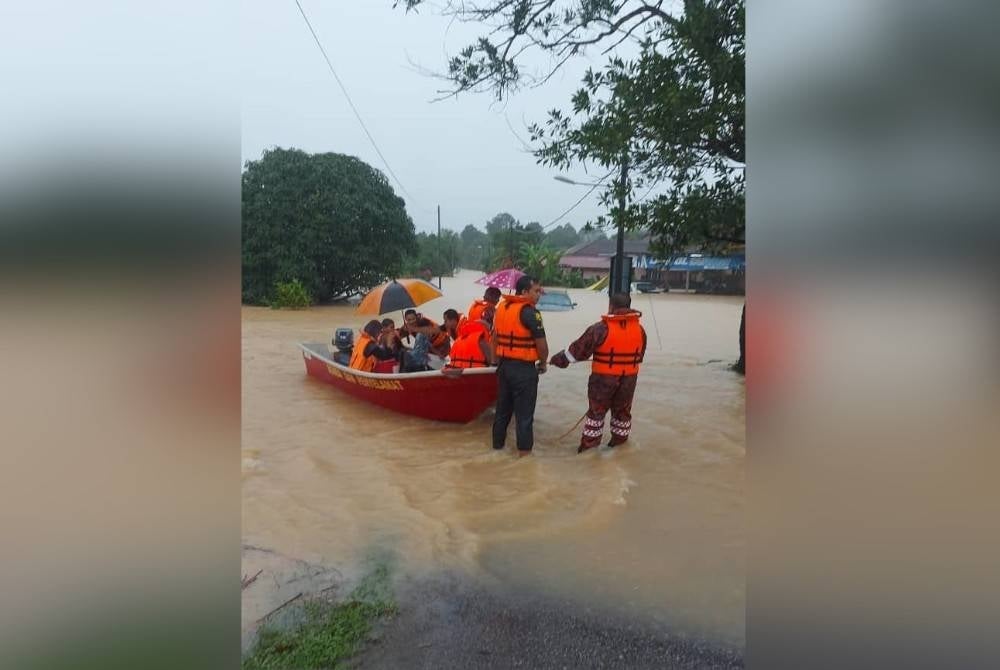 Anggota Bomba sedang membantu memindahkan penduduk yang terjejas banjir. - Foto bomba