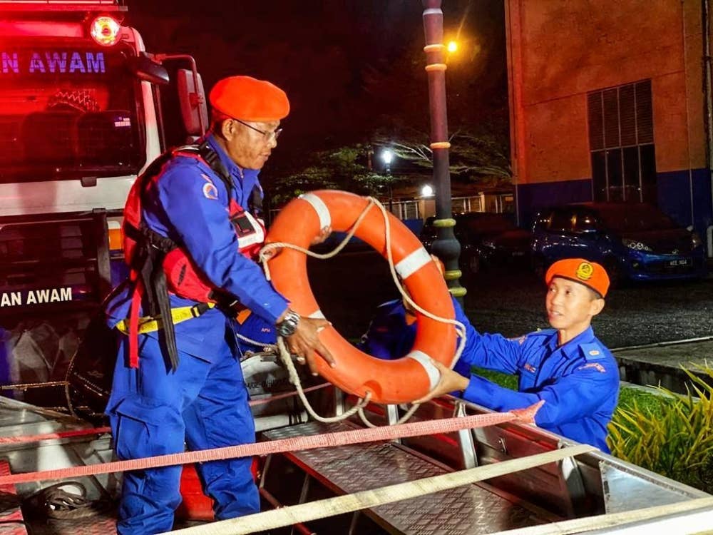 Mohd Muaz (kanan) membantu anggota mengisi peralatan ke dalam bot.