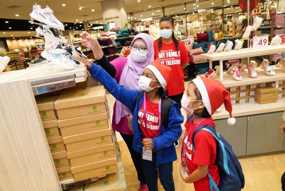 
Sekarelawan membantu kanak-kanak memilih kasut pada program Mesra AEON di AEON Mall Tebrau City, Johor.