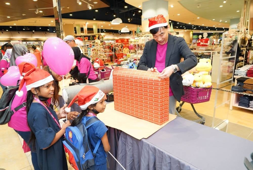Timbalan Pengarah Urusan AEON, Tsugutoshi Seko (kanan) membalut hadiah bersama-sama dua kanak-kanak di AEON Mall Tebrau City, Johor.