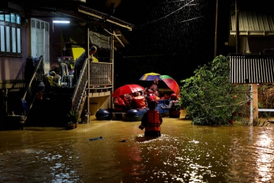 Anggota pasukan JBPM membantu menyelamatkan para penduduk yang terperangkap akibat banjir di Kampung Pulau Rusa Hulu malam tadi. - Foto Bernama