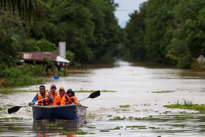 Anggota Pertahanan Awam menaiki bot bagi meninjau laluan utama dari Pasir Mas ke Rantau Panjang yang terputus sepenuhnya ketika tinjauan di Pasir Mas hari ini. - Foto Bernama