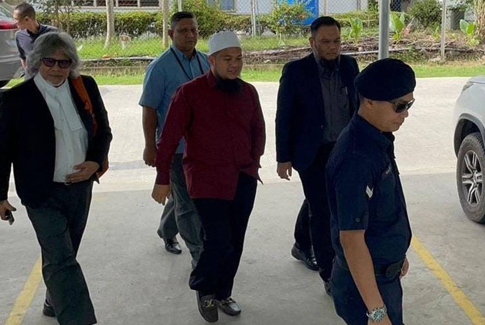 Ebit diiringi peguamnya, Ram Singh (kiri) ketika tiba di Mahkamah Majistret Tenom pada Rabu.