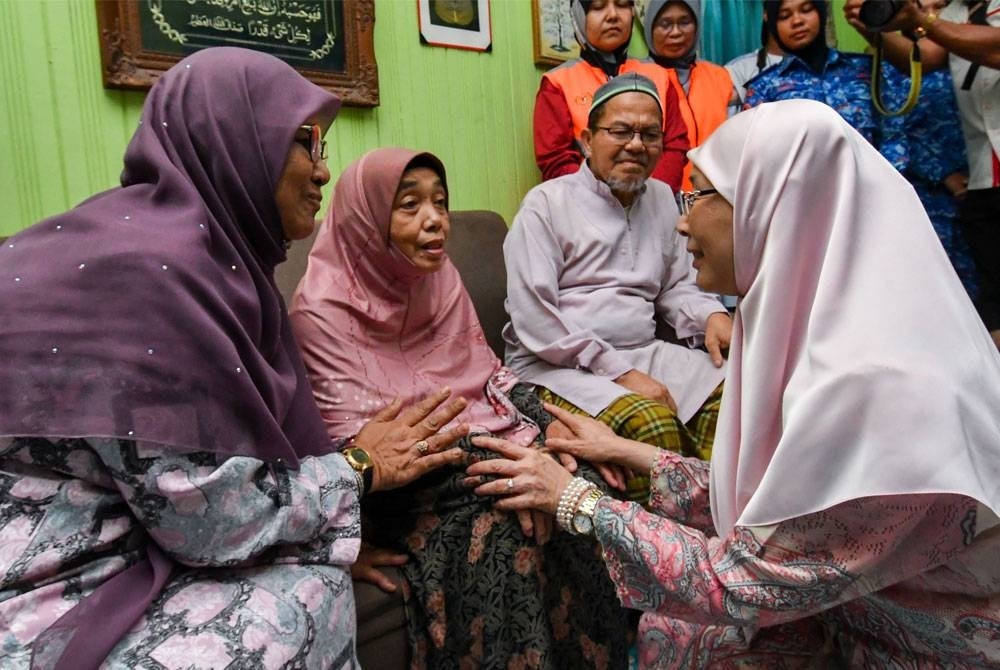 Wan Azizah (kanan) bertanyakan khabar kepada ibu mangsa Zainun Sulaiman, 62, (dua dari kiri) sewaktu menziarahi keluarganya di Kampung Bendang Surau dekat Morak pada Rabu. - Foto Bernama