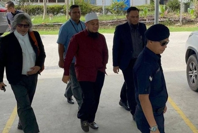 Ebit diiringi peguamnya, Ram Singh (kiri) ketika tiba di Mahkamah Majistret Tenom pada Rabu.