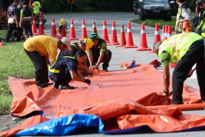 Kakitangan Jabatan Kerja Raya (JKR) memasang kanvas sementara di lereng tanah runtuh -Foto Bernama