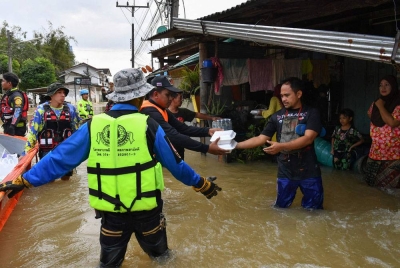 Pekerja agensi bencana mengagihkan makanan dan minuman kepada mangsa banjir di Sungai Kolok di Selatan Thailand pada Rabu. - Foto AFP